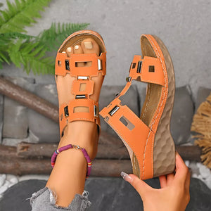 Orange open-toe wedge sandals with geometric cutouts and silver accents.