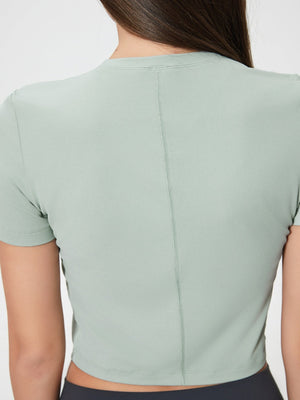 Sage green cropped performance crew neck top with short sleeves and a back seam detail.