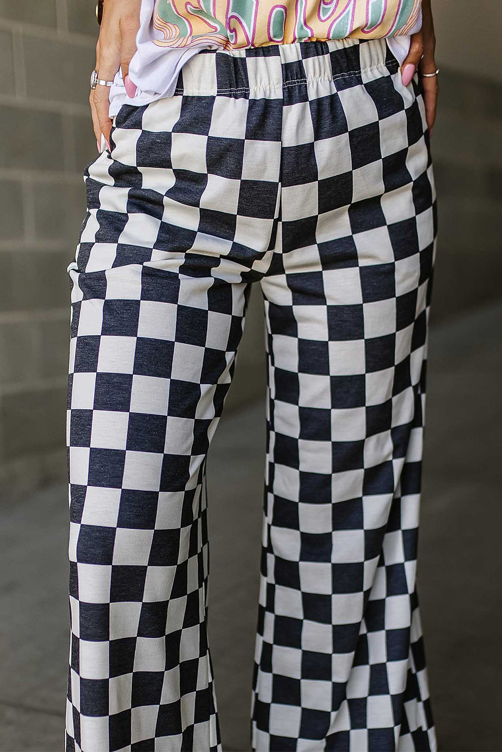 Checkerboard palazzo trousers in black and white with a wide leg and elastic waistband.