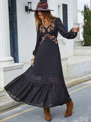 Black polka dot maxi dress with embroidered floral detail, V-neck, long sleeves, and ruffled hem.
