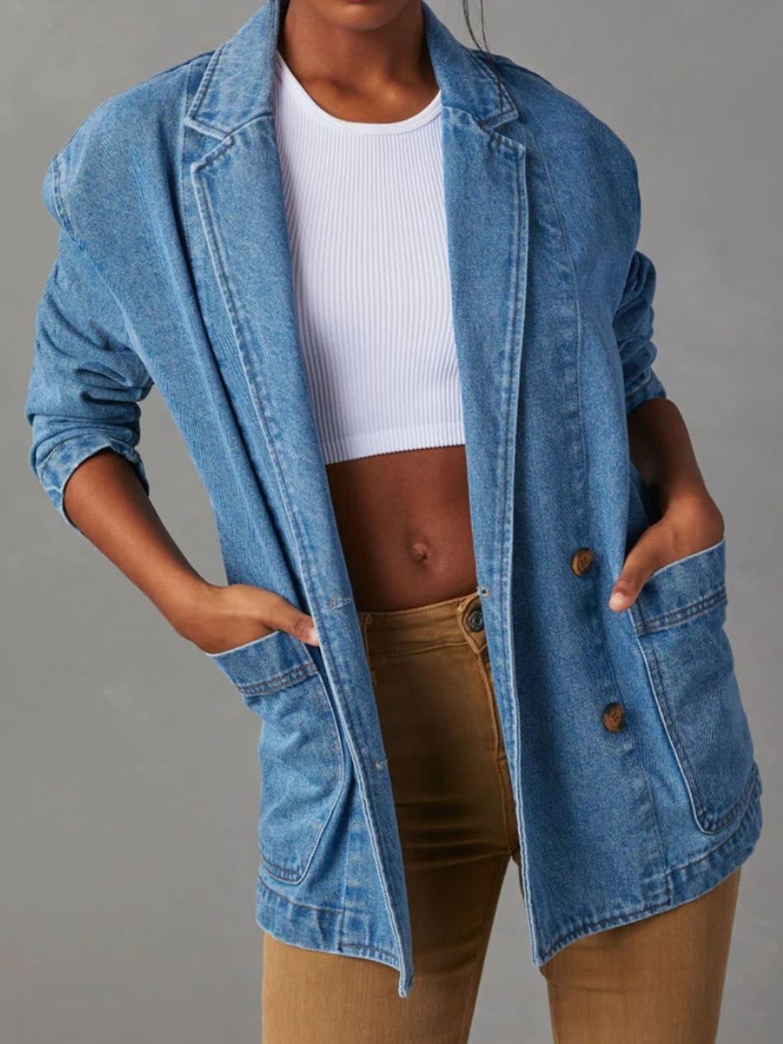 Denim blazer in dusty blue with structured shoulders and buttoned front, styled with a white crop top.