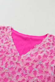 Fuchsia pink blouse with floral appliqué mesh overlay and V-neck.