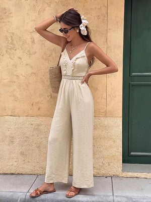 Lace-trimmed spaghetti strap romper in cream with wide legs and V-neck.