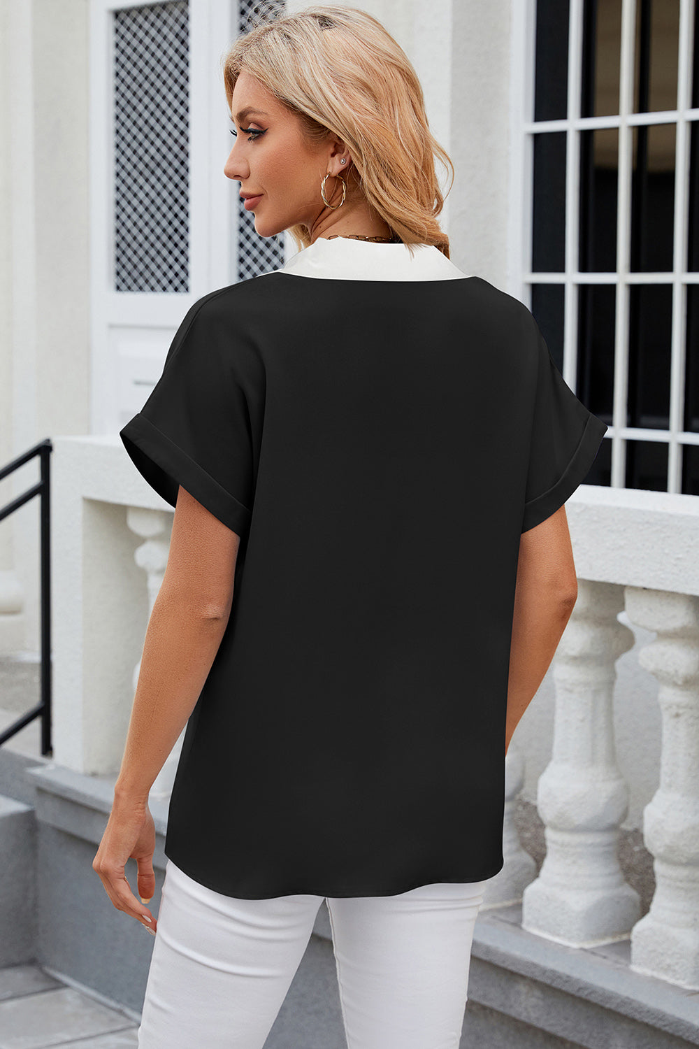 Black blouson top with white contrast V-neck and cuffed short sleeves.