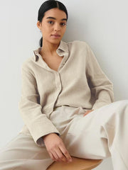 Beige textured cotton overshirt with relaxed fit and button front, styled casually.