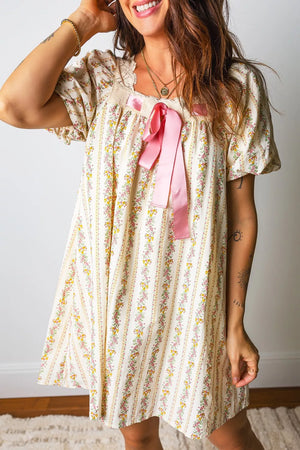 Floral mini dress with lace trim, puff sleeves, and pink bow detail on a striped floral print.