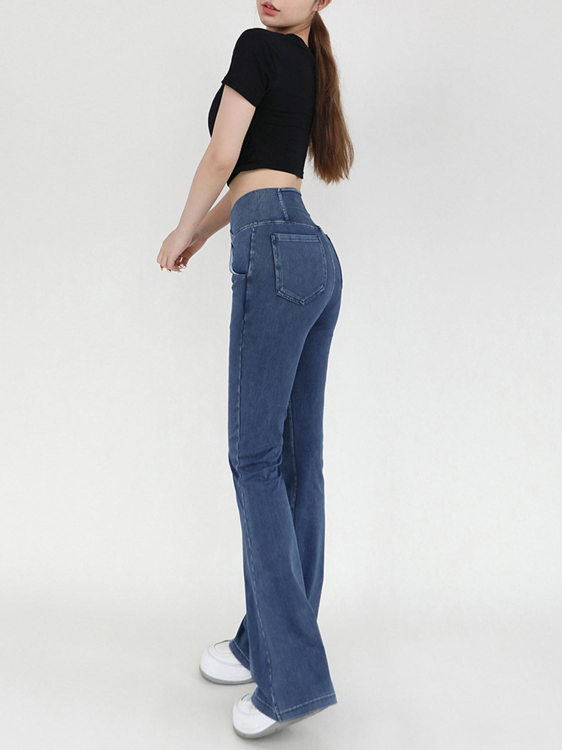 Medium wash denim flare jeans with crossover waist detail.