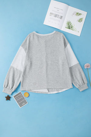 Light gray colorblock sweatshirt with crew neck, long sleeves, and textured paneling.