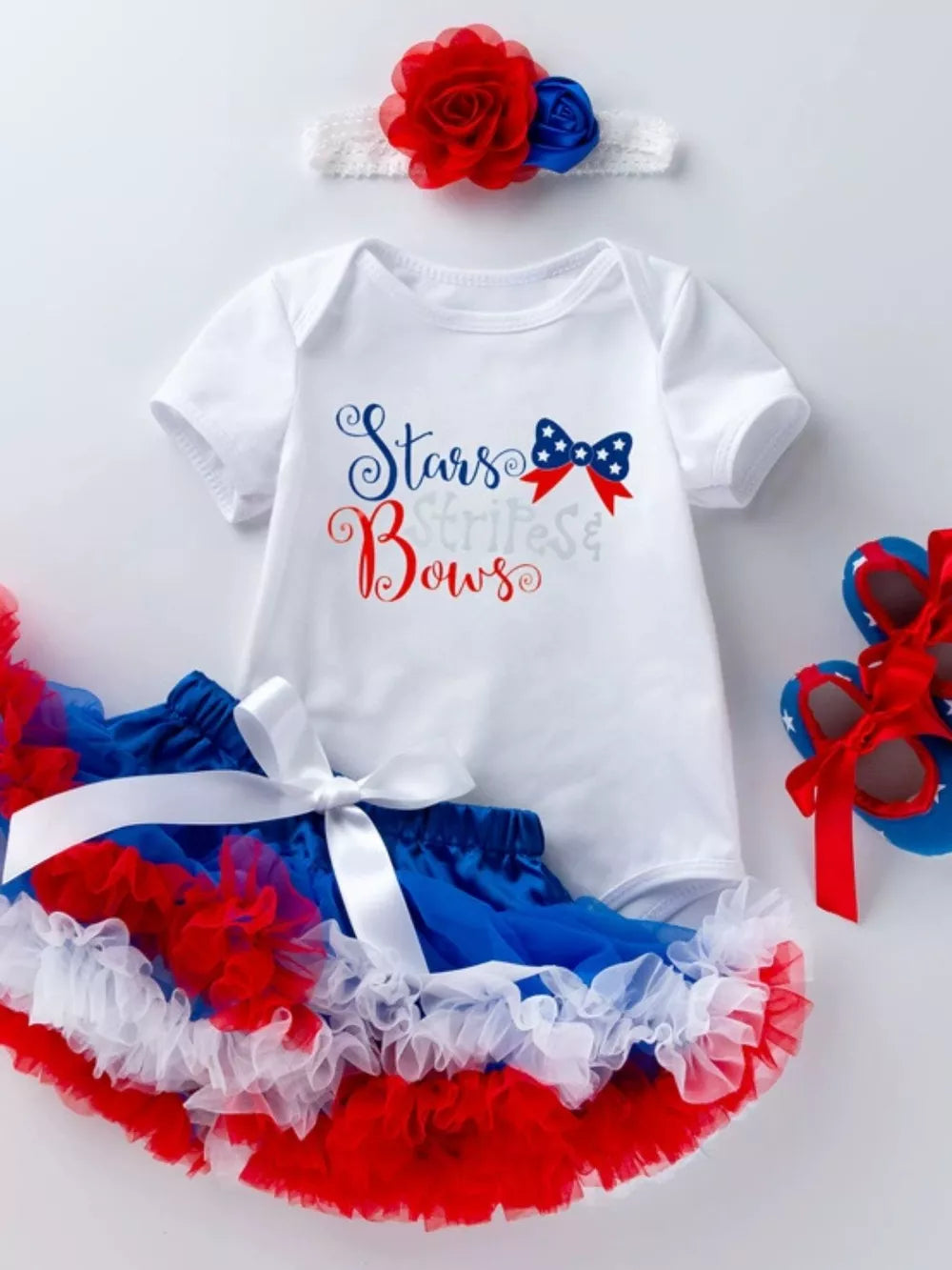 Patriotic baby outfit with white bodysuit, ruffled tutu, and floral headband.