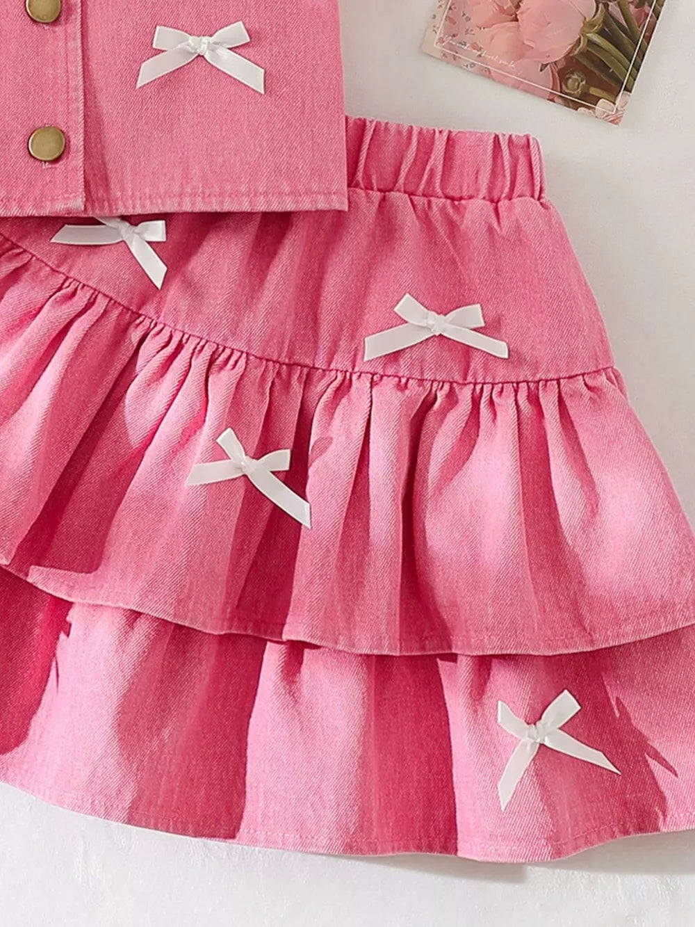 Pink denim halter set with white bow accents and tiered ruffle skirt.