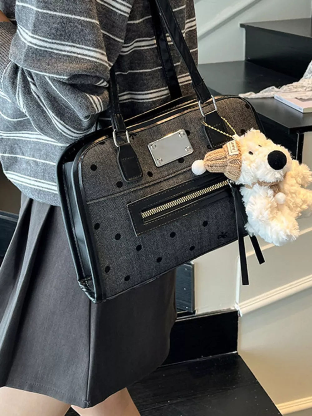 Black polka dot shoulder bag with a fuzzy dog charm and silver plate detail.