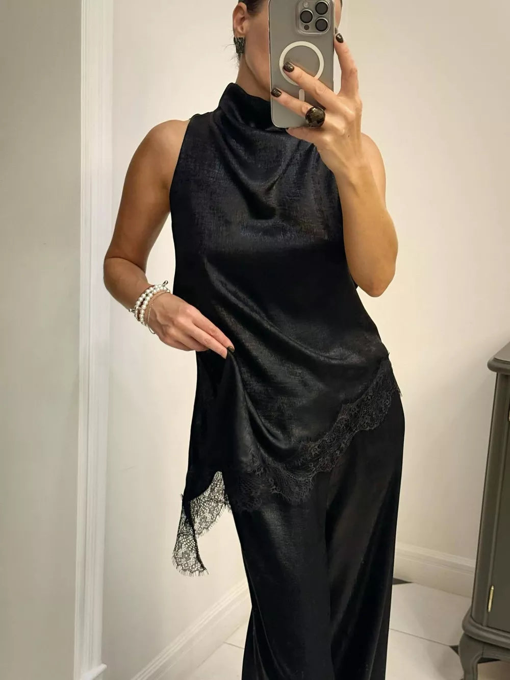 Black asymmetrical lace trim cami top with a mock neck and sleeveless design.