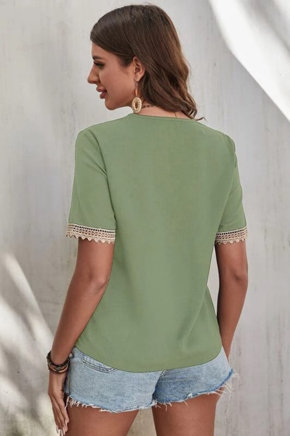Light green V-neck blouse with lace trim on short sleeves.