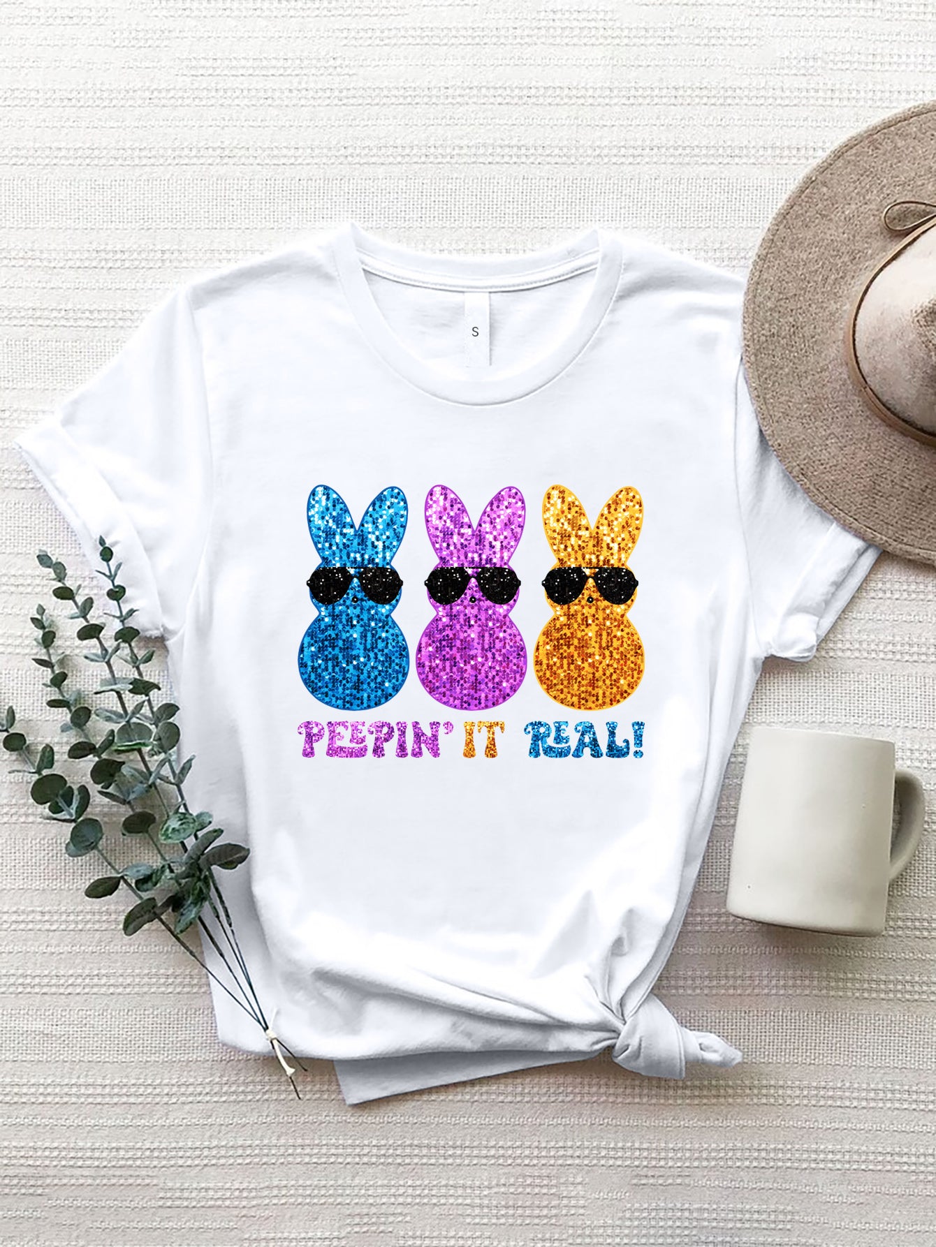 White t-shirt with glitter bunnies wearing sunglasses and "Peepin' It Real!" graphic.