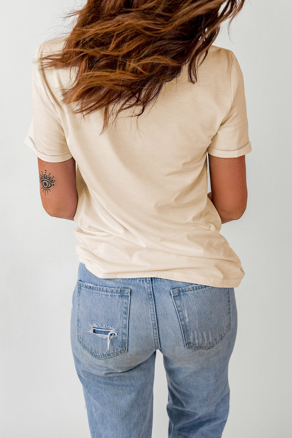 Cream basic t-shirt with short sleeves and a crew neck, styled with distressed denim jeans.