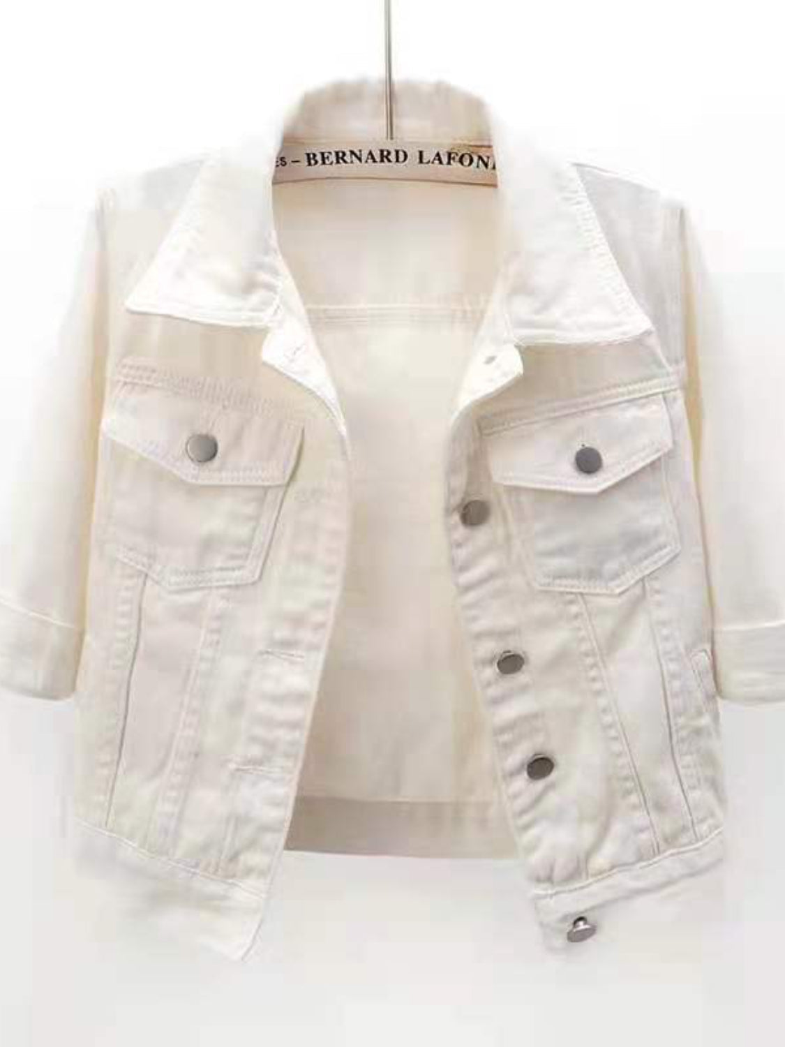 White denim trucker jacket with cropped sleeves and button flap chest pockets.