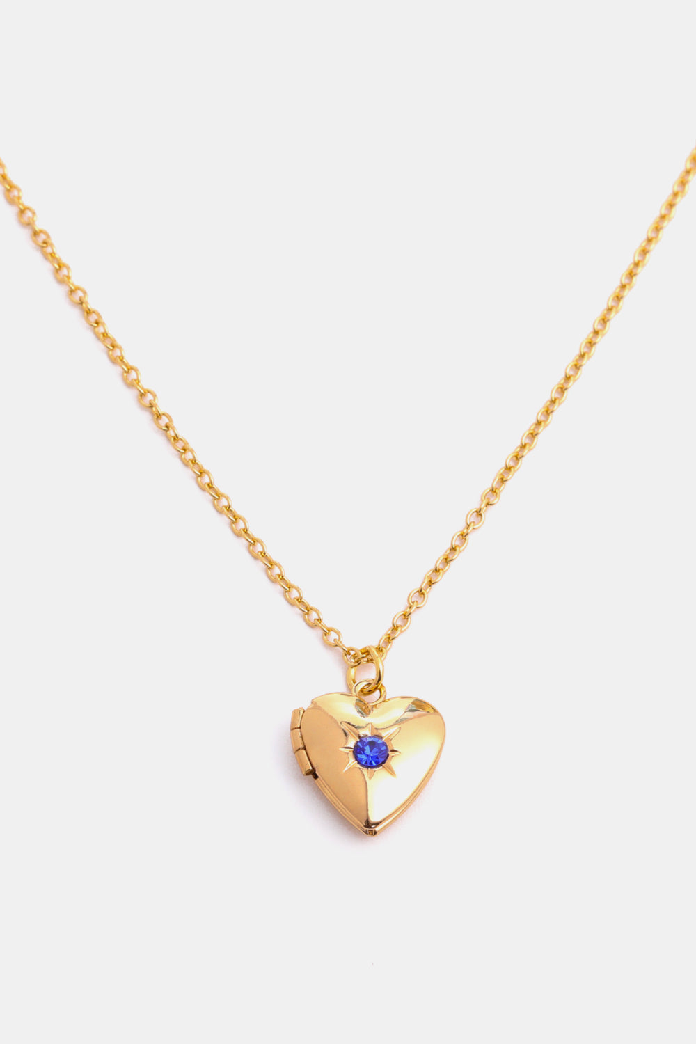 Gold heart locket necklace with blue gemstone and starburst detail on delicate chain.