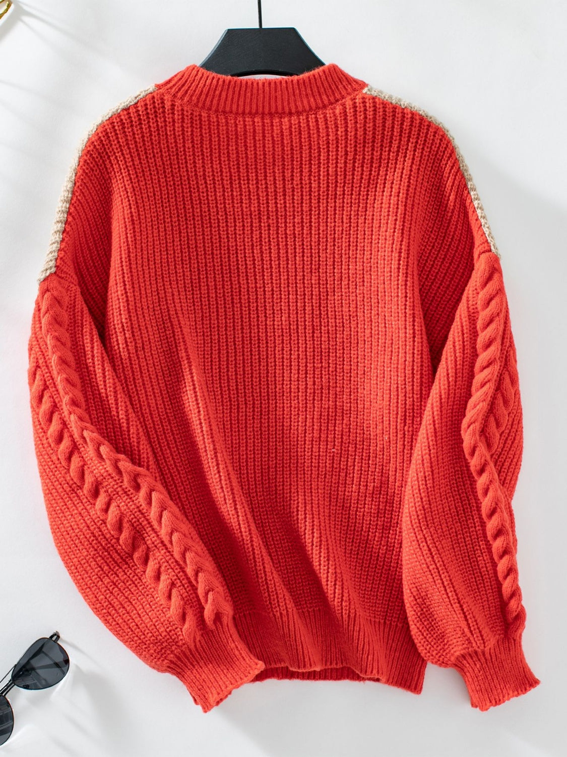 Orange-red cable knit sweater with tan chevron detail on shoulders and sleeves.