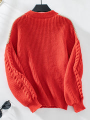 Orange-red cable knit sweater with tan chevron detail on shoulders and sleeves.