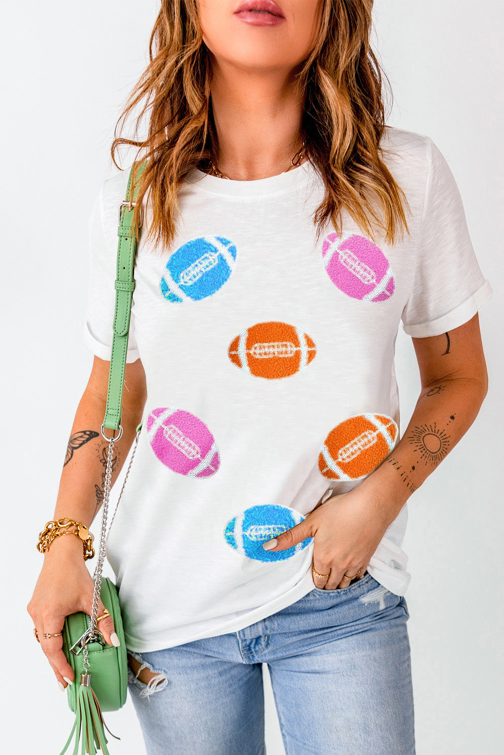 White t-shirt with rolled sleeves and scattered colorful football graphics.