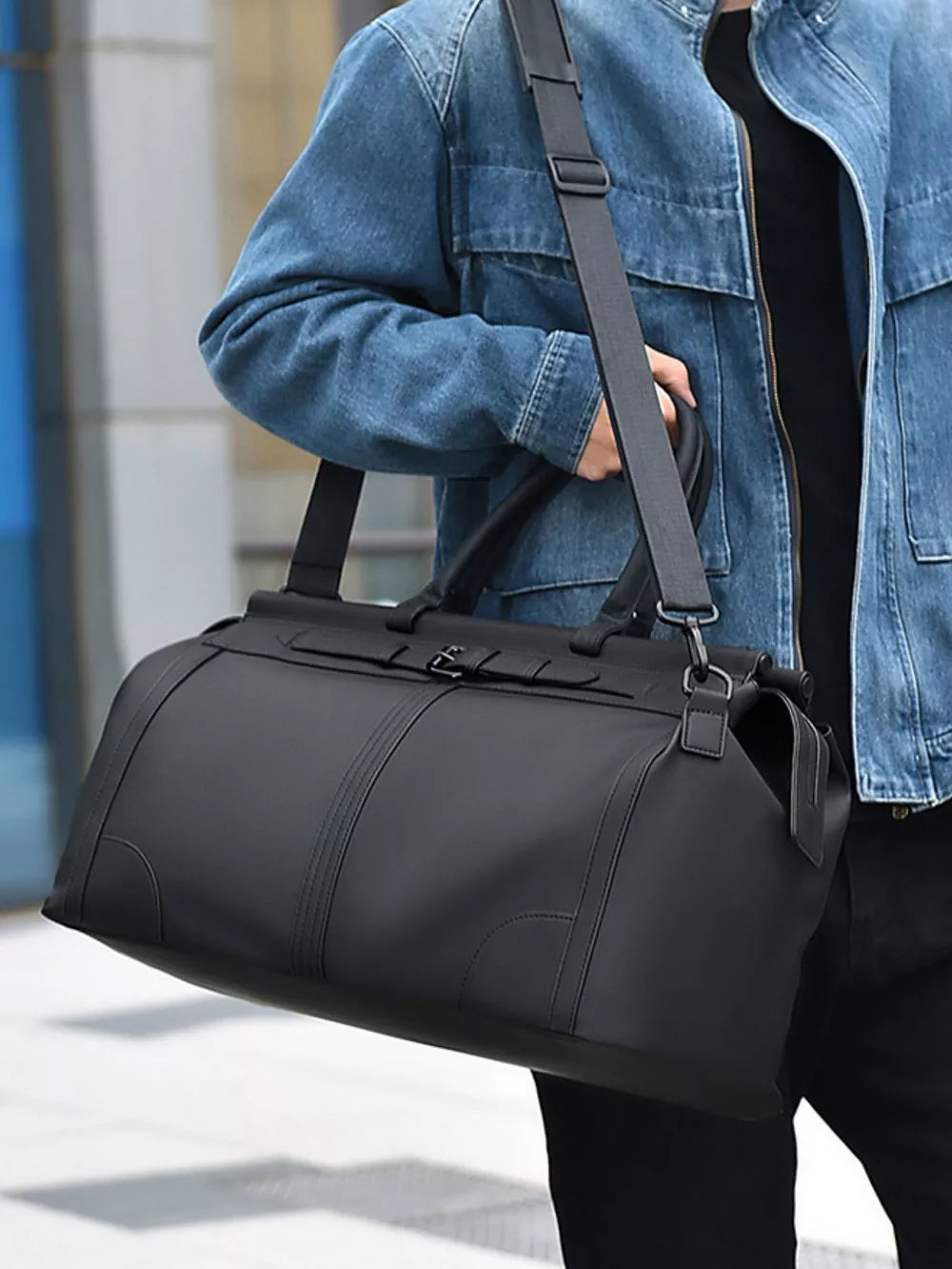 Black Oxford cloth travel duffel bag with adjustable shoulder strap and top handles.