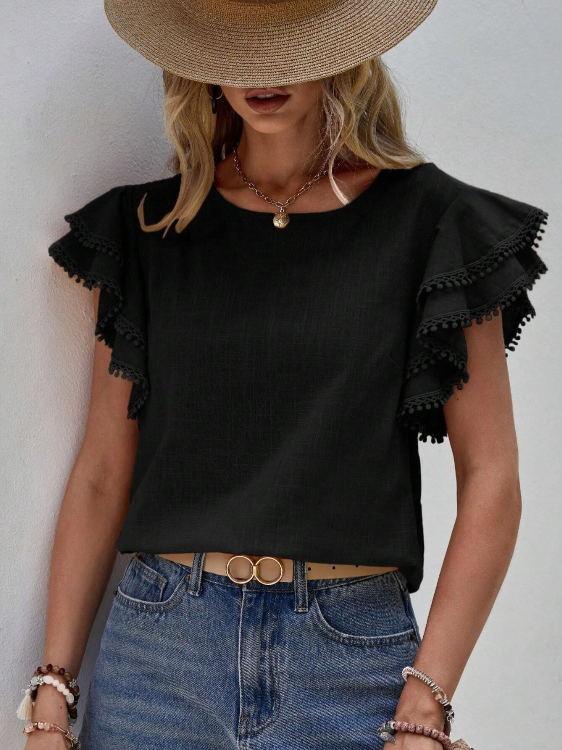 Black ruffle sleeve blouse with pom-pom trim and crew neck.