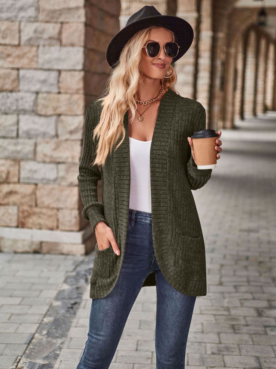 Textured ribbed open-front cardigan in dark green with pockets, styled casually with jeans.
