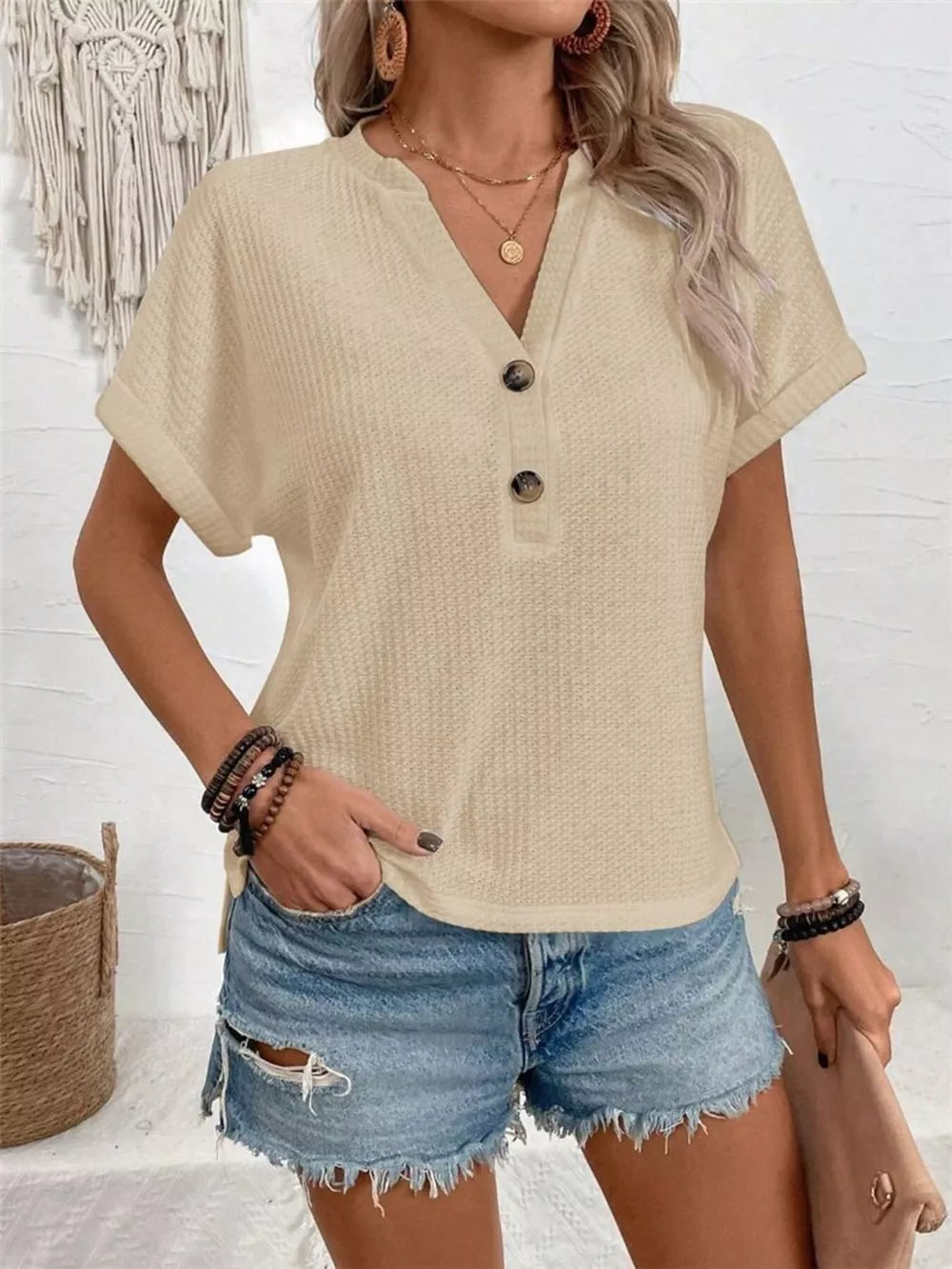 Apricot V-neck waffle knit t-shirt with button detail and short sleeves.
