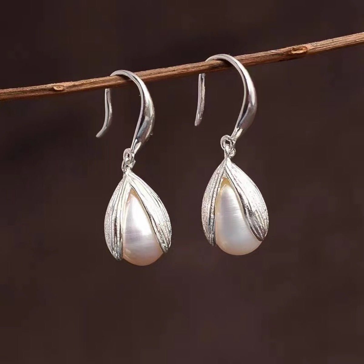 Lustrous pearl drop earrings with silver leaf-shaped settings.