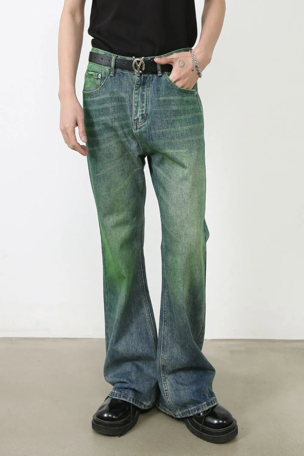 Acid wash flare denim jeans in medium with a green gradient effect, styled with a black belt and platform shoes.