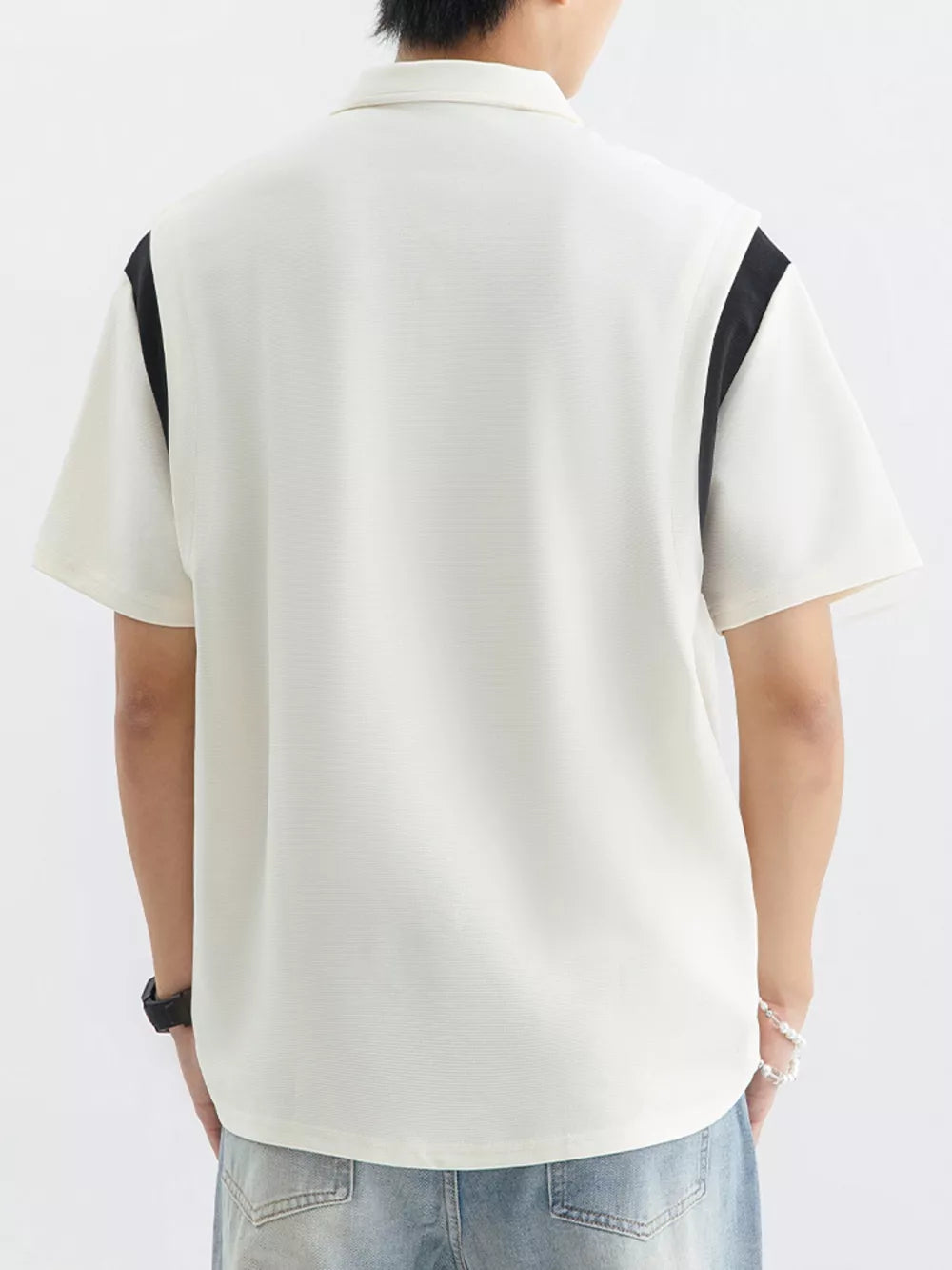 Men's beige cotton polo shirt with contrast black shoulder panels and textured fabric.