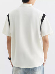 Men's beige cotton polo shirt with contrast black shoulder panels and textured fabric.