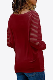 Wine raglan v-neck top with sheer striped sleeves and pleated cuffs.