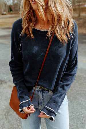 Navy waffle knit raglan sweater with ruffled cuffs and contrast trim.