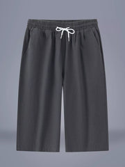 Relaxed plus size cropped sweatpants in dark gray with drawstring waist and pockets.