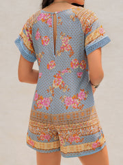 Light blue floral embroidered romper with short sleeves and cutout back detail.