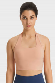 Nude halter neck sports bra with square neckline and ruched back detail.