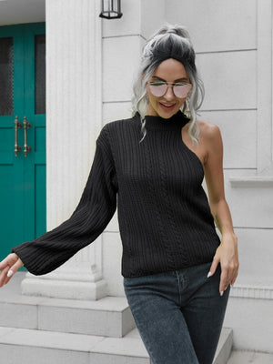 Black asymmetric cable knit sweater with one shoulder exposed.