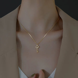 Gold delicate key pendant necklace with crystal accents on a thin chain.