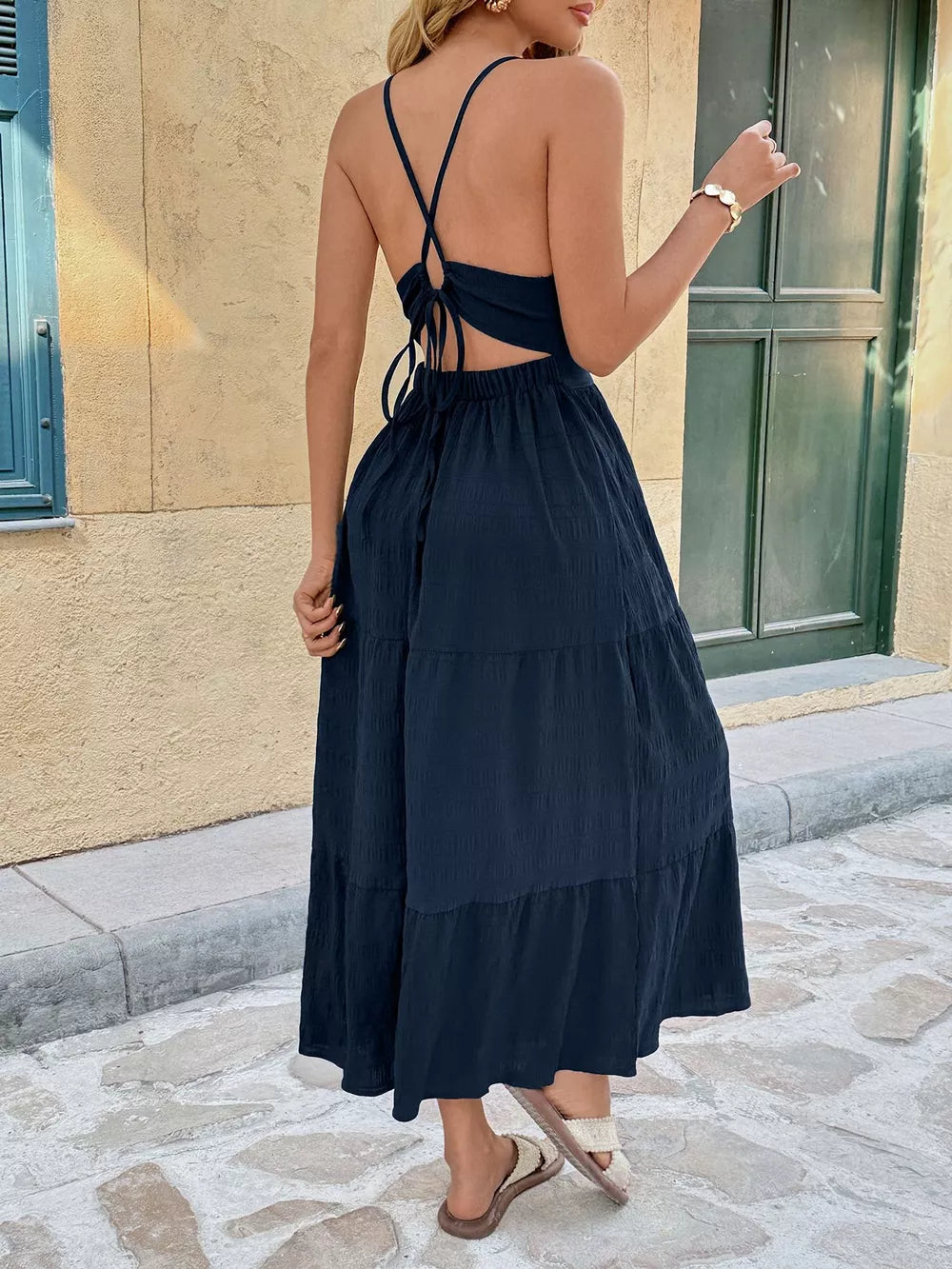 Navy ruched midi dress with halter tie back and tiered skirt.