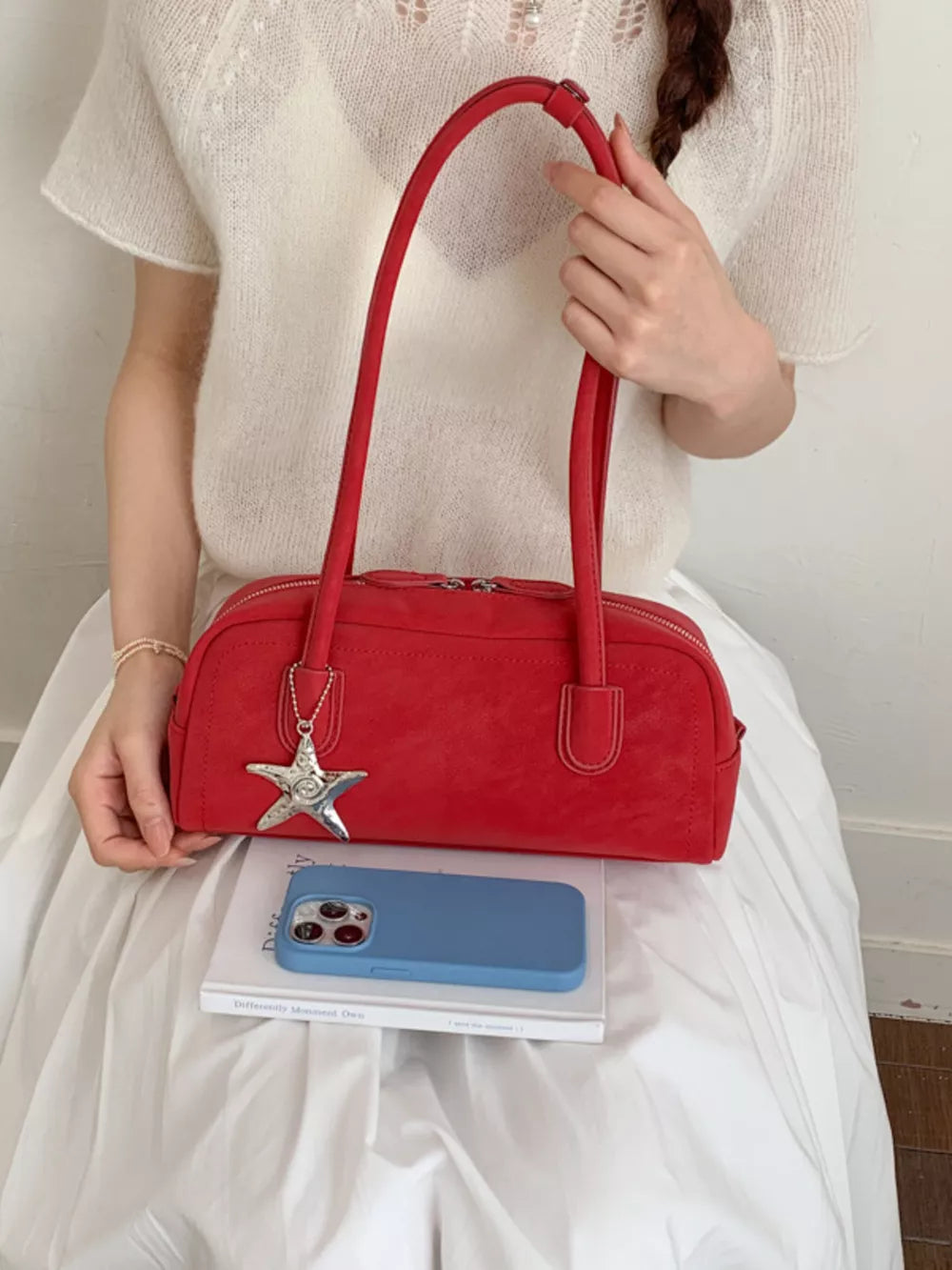 Red shoulder bag with star charm and double zipper closure.