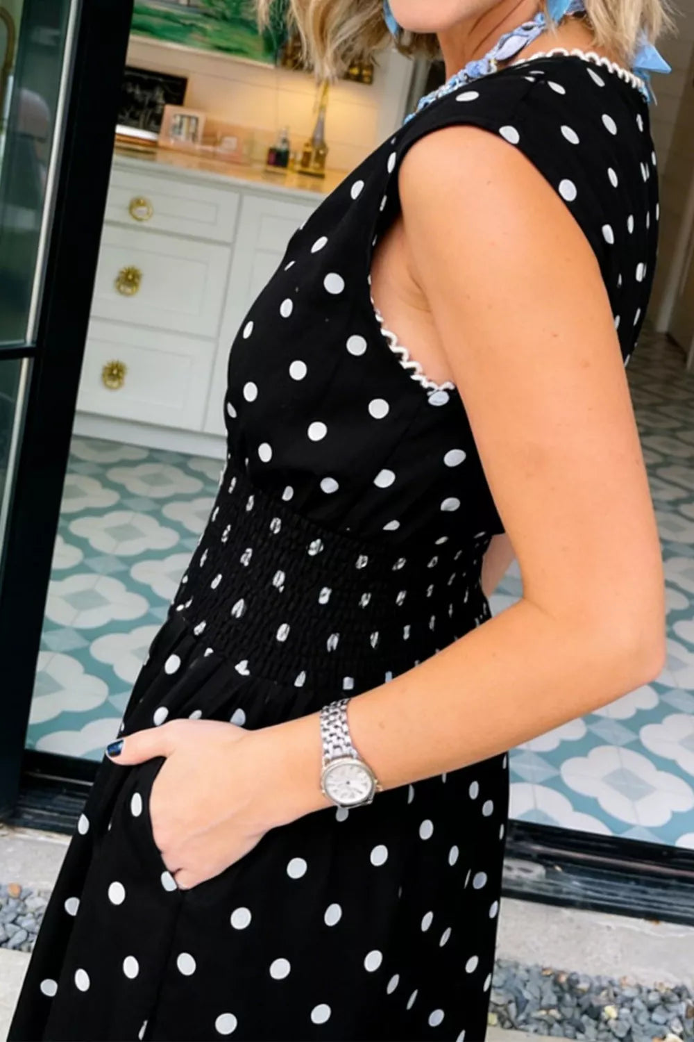 Black polka dot midi dress with smocked waist and ruffled neckline detail.
