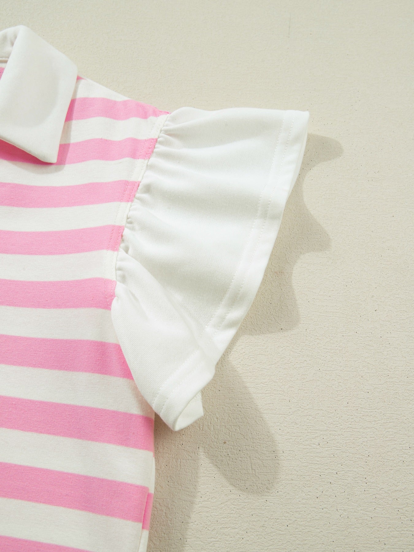Cotton blouse with pink and white stripes and ruffled sleeves.