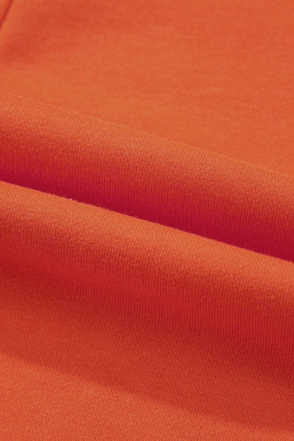 Orange colorblock romper with V-neck and patch pockets, close-up of fabric texture.