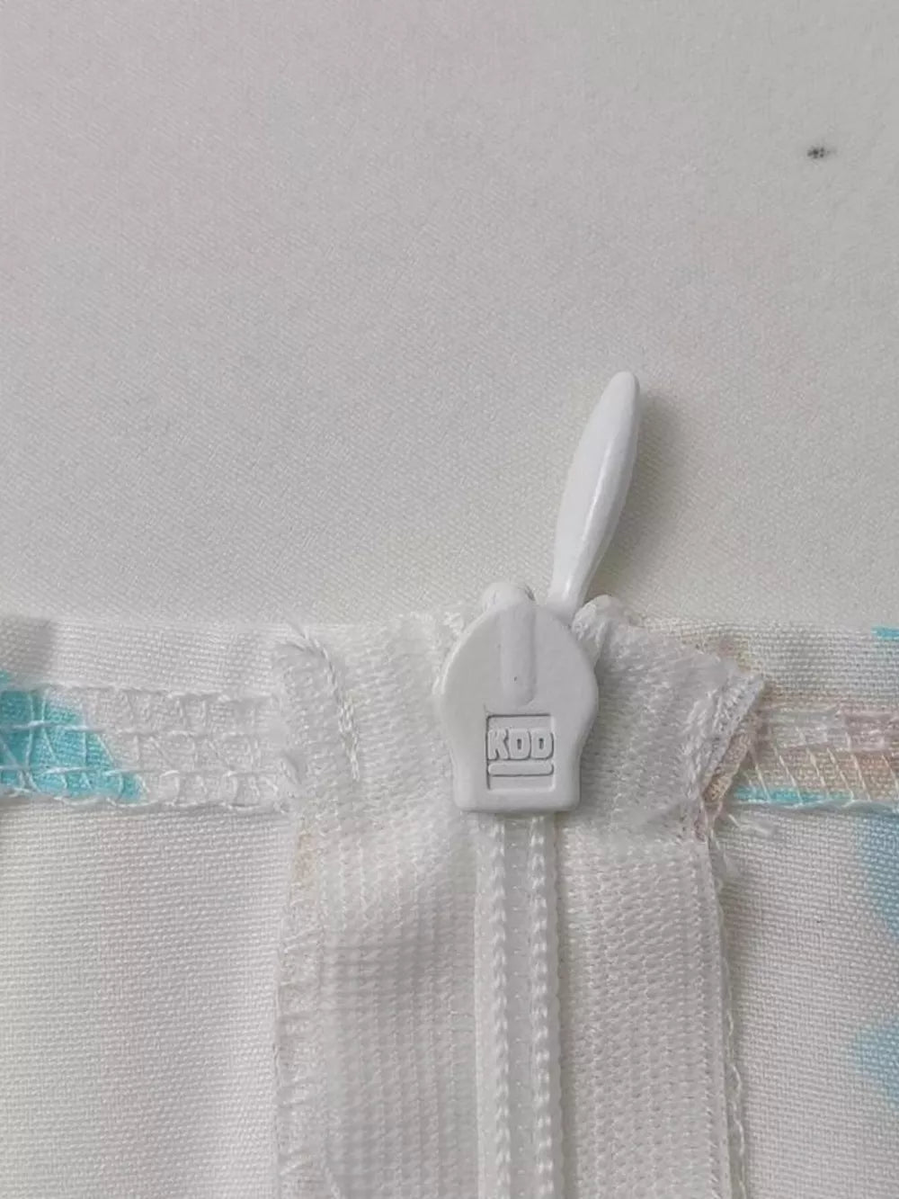 Floral maxi dress detail showing white zipper and pastel floral print.