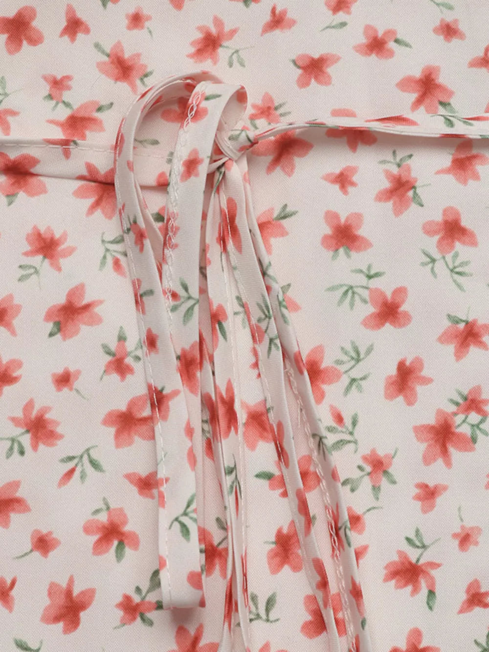 Floral mini dress with V-neck and puff sleeves, featuring a tie detail.