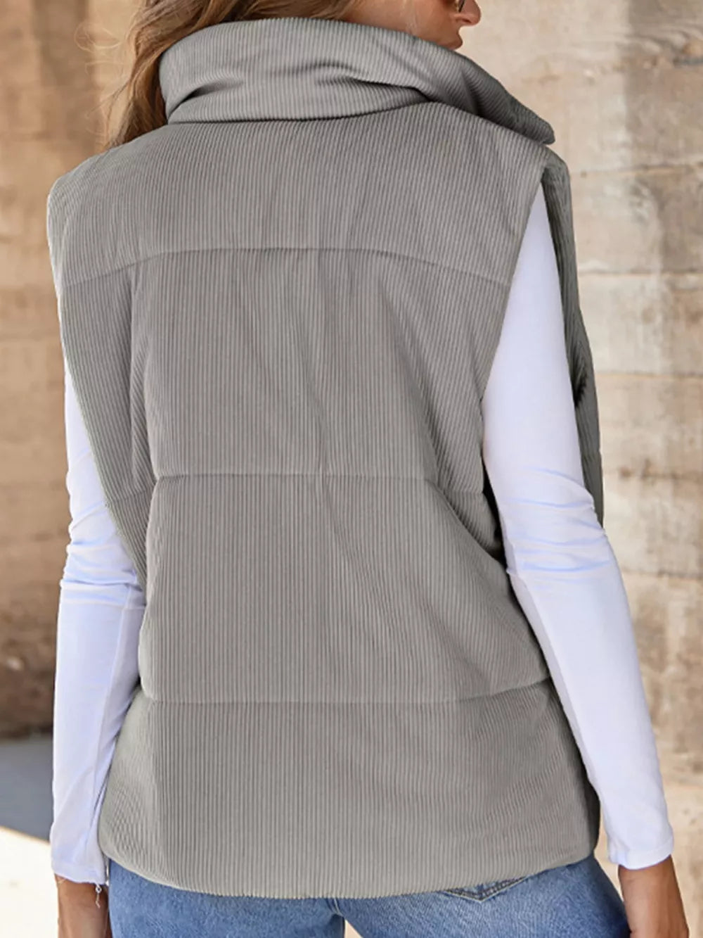 Gray ribbed corduroy zip-up vest coat with a high funnel neck, worn over a white long-sleeve shirt.