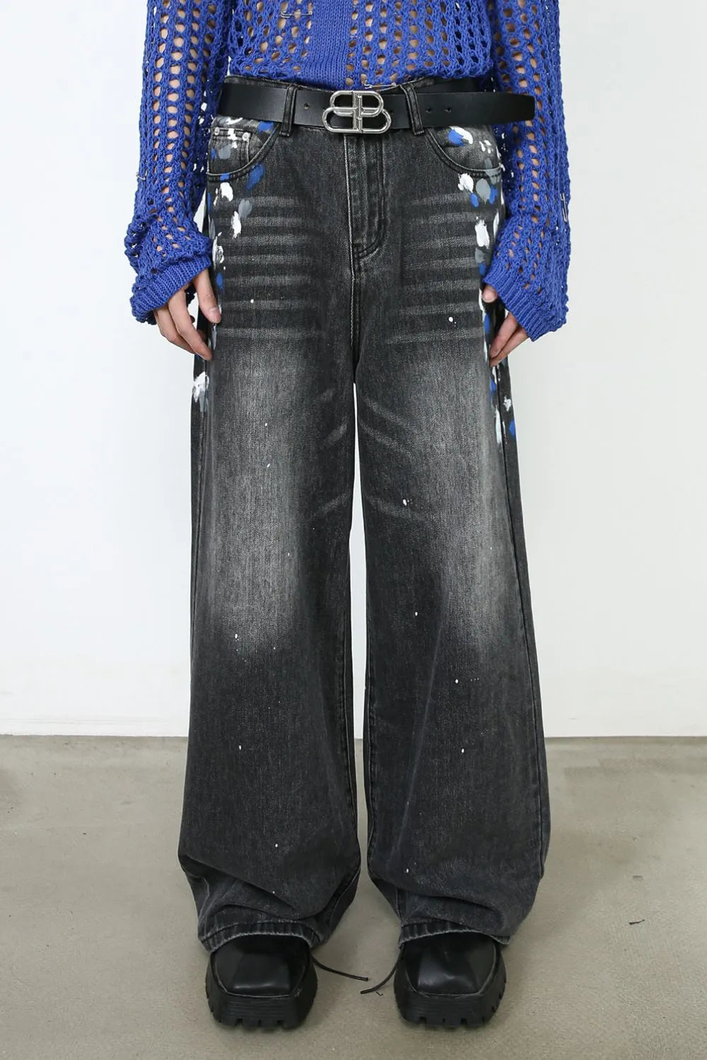 Dark wash denim jeans with painterly splatters and a wide flare leg.