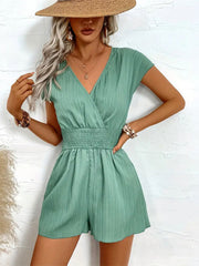 Textured wrap romper with smocked waist and short sleeves in a light green hue.