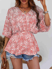 Abstract print cinched waist blouse in scarlet and white with V-neck and short sleeves.